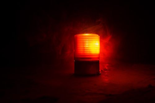 Red warning light glowing in the dark, symbolizing the risks and red flags sellers face when dealing with potential buyers in hospitality business sales.