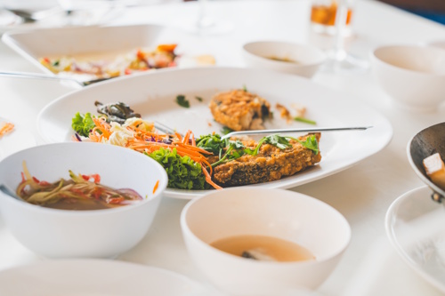 Restaurant table with unfinished meals and leftovers on plates, illustrating the issue of food waste in hospitality.